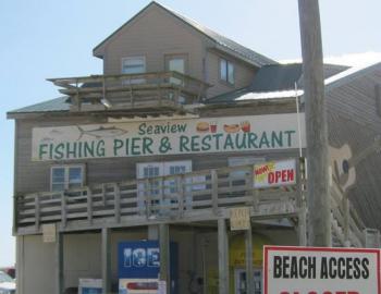 a tall, wooden building with a sign that reads "Seaview Fishing Pier & Restaurant" in green text