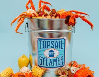 a bowl of crab legs and clams with the words "Topsail Beach" written in blue on the front