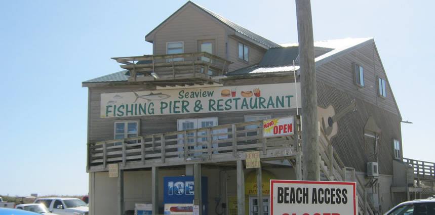 a tall, wooden building with a sign that reads "Seaview Fishing Pier & Restaurant" in green text